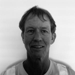 A black and white photo of a man smiling.