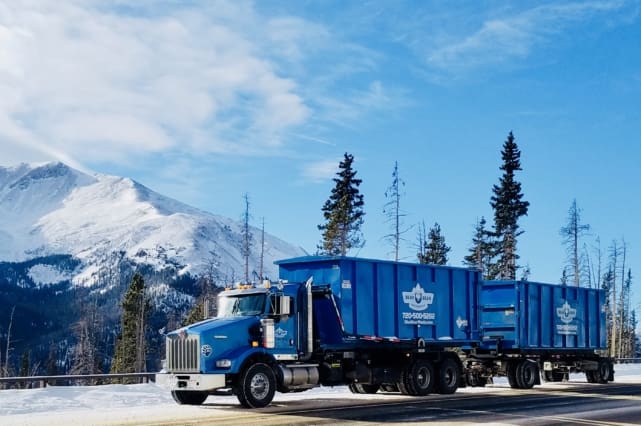 A blue truck is parked in the snow