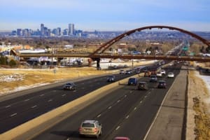 A highway with cars driving on it and the city in the background.