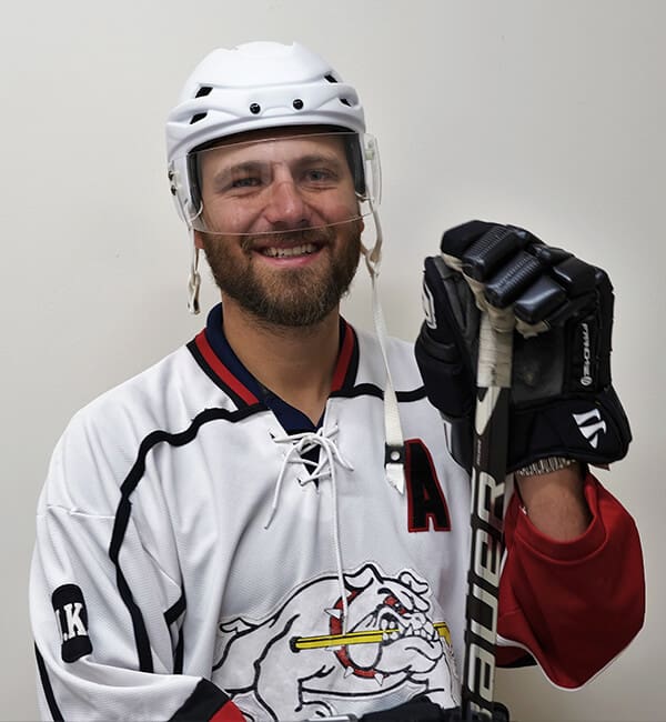 A man in white hockey uniform holding a stick.