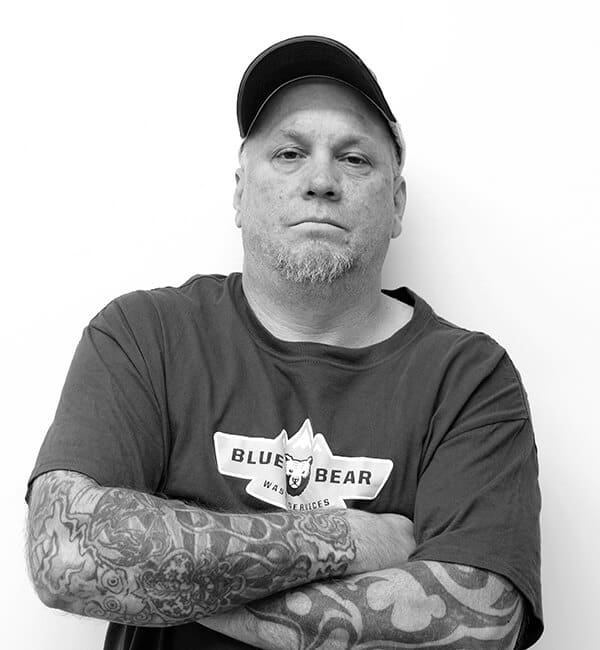 A man with tattoos and baseball cap posing for the camera.