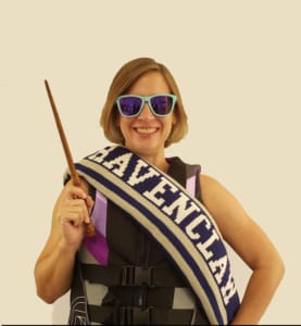 A woman holding a wand and wearing a sash.