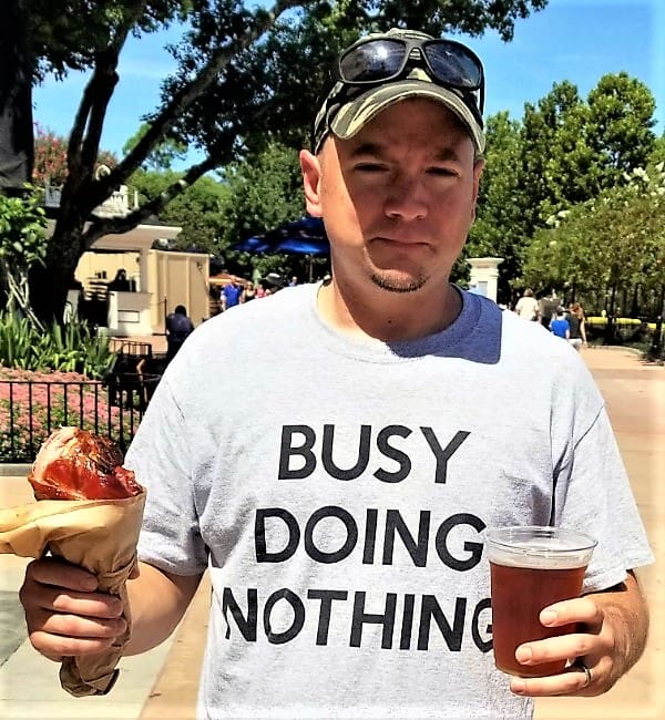 A man holding a sandwich and beer in his hand.