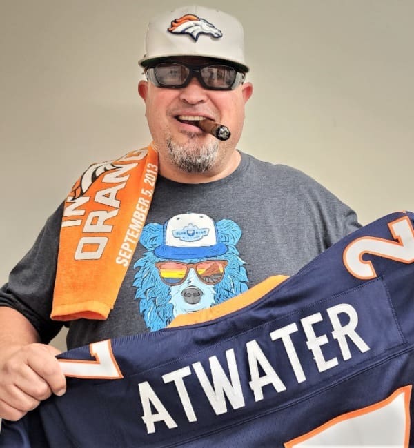 A man holding up an orange and white football jersey.