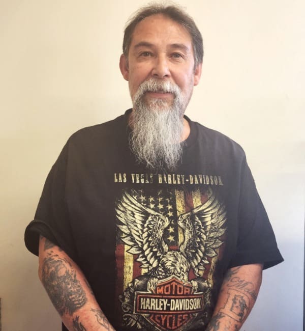 A man with long white beard and tattoos.