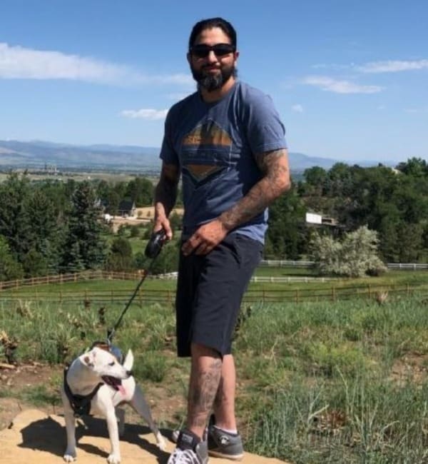 A man standing next to his dog on a leash.